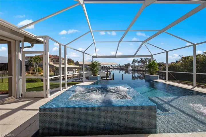 View of pool featuring pool water feature, a lanai, a water view, and a dock