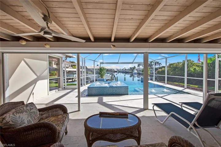 Sunroom with beamed ceiling, a water view, ceiling fan, and wood ceiling