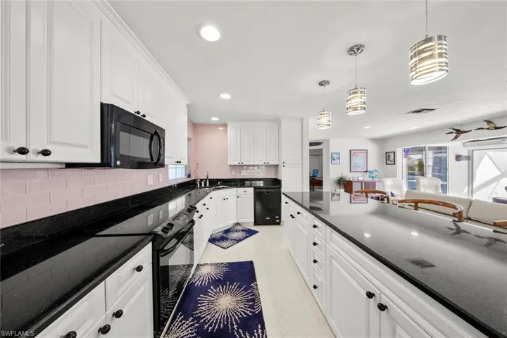 Kitchen with pendant lighting, white cabinets, and black appliances