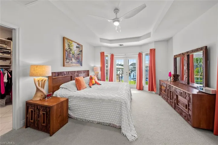 Carpeted bedroom featuring french doors, access to outside, multiple windows, and ceiling fan