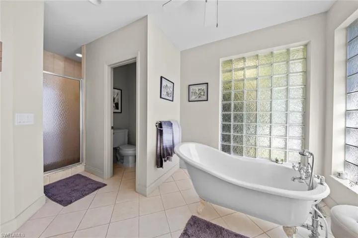 Bathroom with tile patterned flooring, separate shower and tub, and toilet
