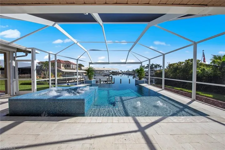 View of pool with a lanai, pool water feature, a water view, and a boat dock