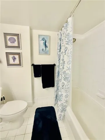 Bathroom featuring shower / bathtub combination with curtain and tile patterned floors
