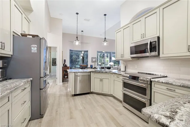 Kitchen with pendant lighting, backsplash, appliances with stainless steel finishes, light hardwood / wood-style floors, and sink