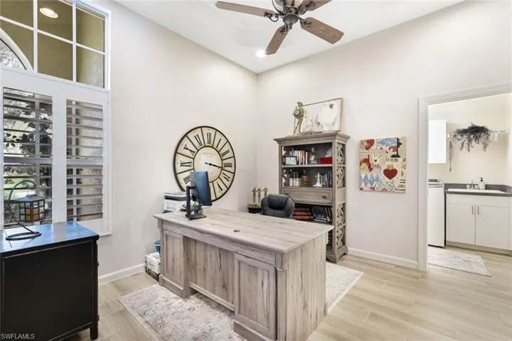 Home office with washer / clothes dryer, ceiling fan, sink, and light wood-type flooring