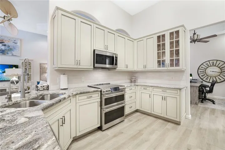 Kitchen with appliances with stainless steel finishes, ceiling fan, backsplash, and light hardwood / wood-style floors