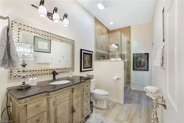 Bathroom featuring walk in shower, toilet, hardwood / wood-style flooring, and vanity