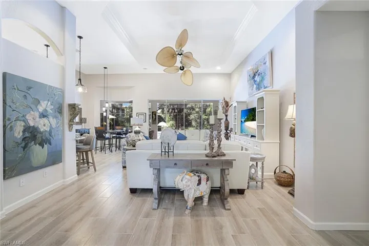 Living room with a tray ceiling, ornamental molding, ceiling fan, and light hardwood / wood-style floors