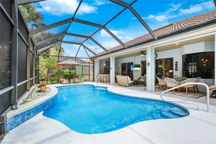 View of pool with glass enclosure, ceiling fan, and a patio area