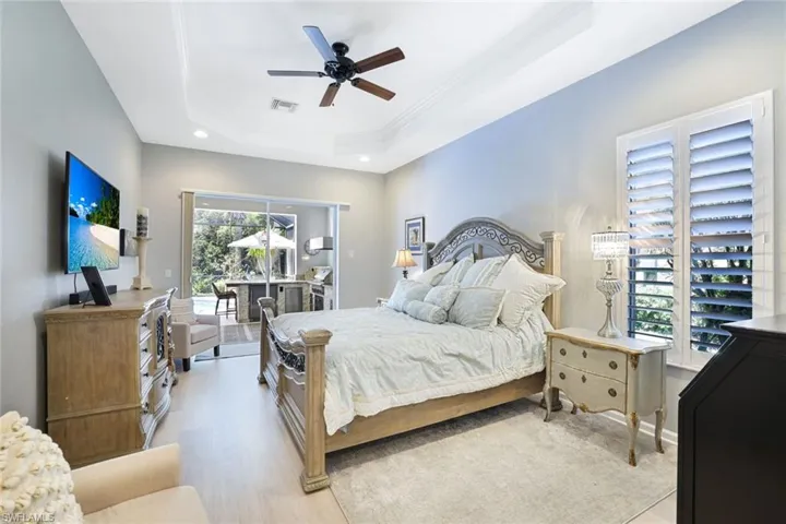 Bedroom featuring ceiling fan, ornamental molding, a tray ceiling, and light hardwood / wood-style floors
