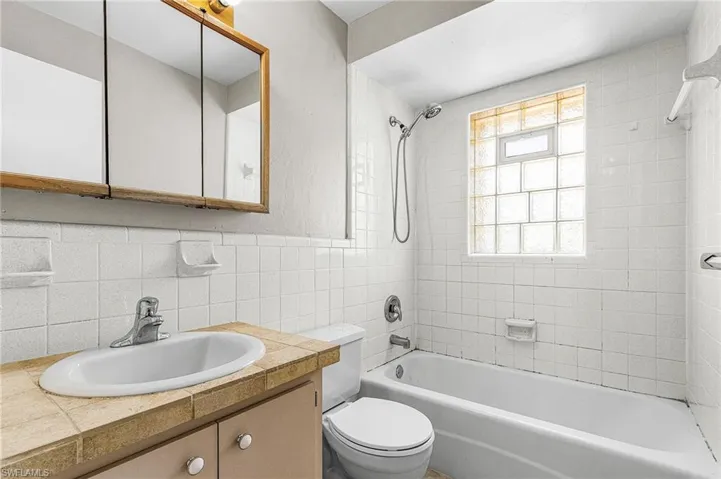 Bathroom with  shower combination, vanity, tile walls, and tasteful backsplash