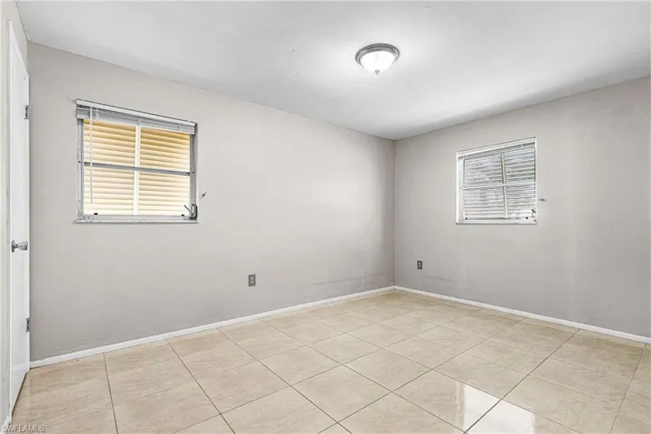 Unfurnished room with light tile patterned flooring and baseboards