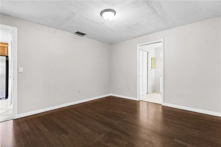Empty room featuring dark wood-style flooring and a textured ceiling
