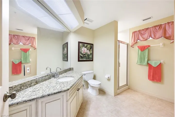 Bathroom featuring tile patterned floors, vanity, toilet, and an enclosed shower