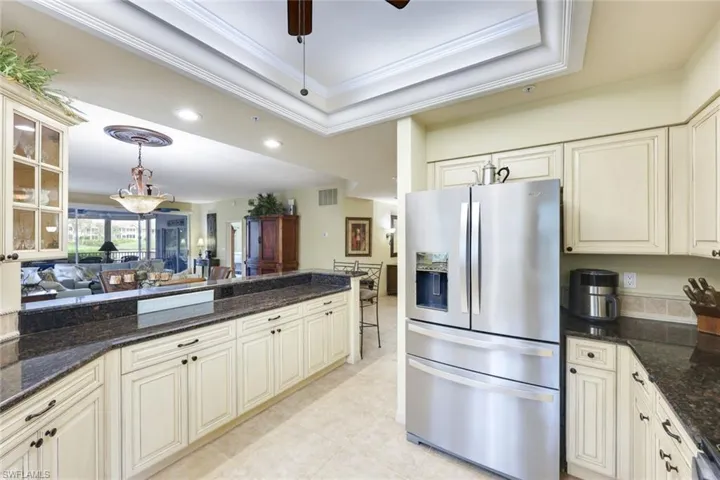 Kitchen with dark stone countertops, stainless steel fridge, crown molding, and decorative light fixtures