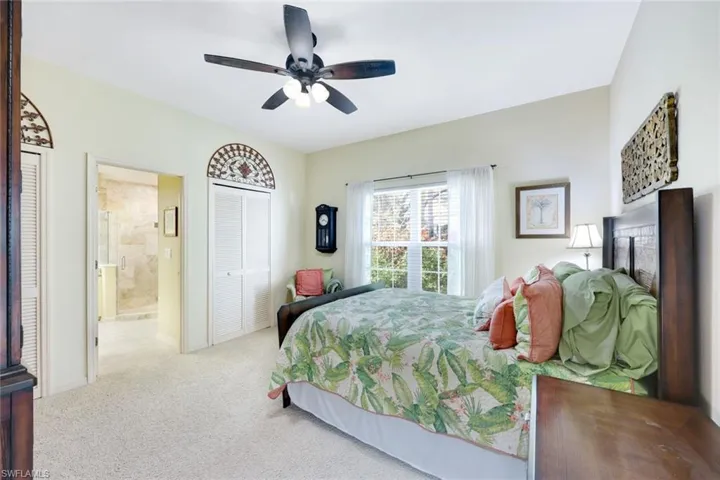 Carpeted bedroom featuring ceiling fan and ensuite bathroom