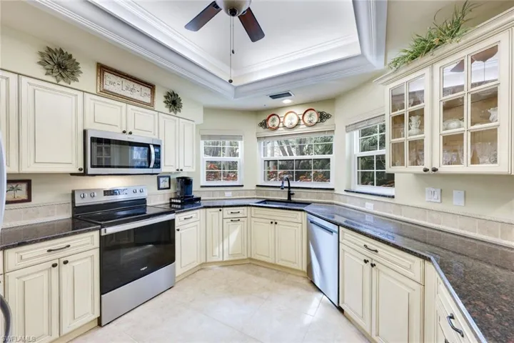 Kitchen featuring appliances with stainless steel finishes, dark stone counters, ornamental molding, and sink
