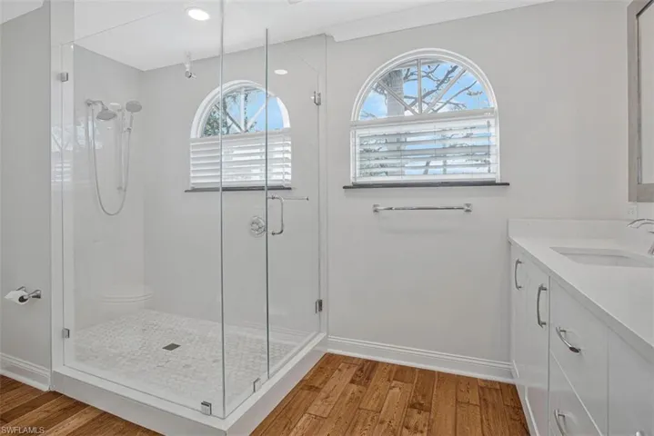 Full bath featuring vanity, light wood finished floors, and a stall shower
