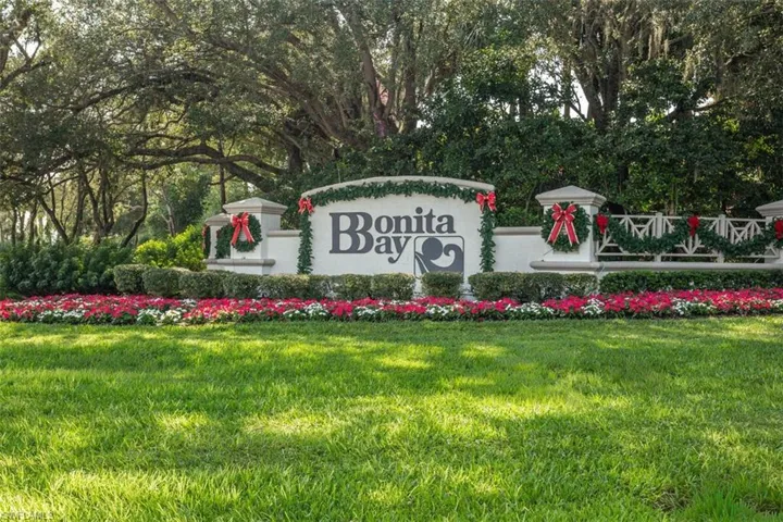 Community sign featuring a yard and view of wooded area