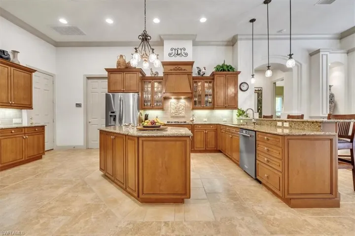 Kitchen featuring wood finish cabinets, a peninsula, light stone counters, glass fronted cabinets, and backsplash