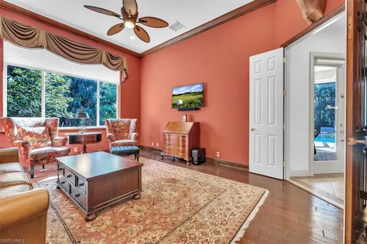 Living room featuring crown molding, ceiling fan, and wood-type flooring
