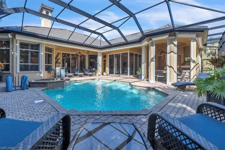 Combined pool / hot tub with glass enclosure, a sunroom, a patio, and outdoor dining area