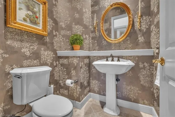 Half bath featuring wallpapered walls and tile patterned floors