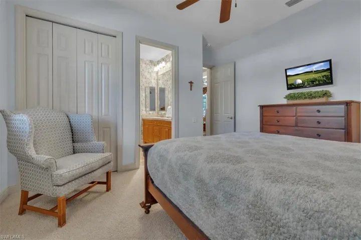 Bedroom featuring light carpet, a ceiling fan, a closet, and connected bathroom