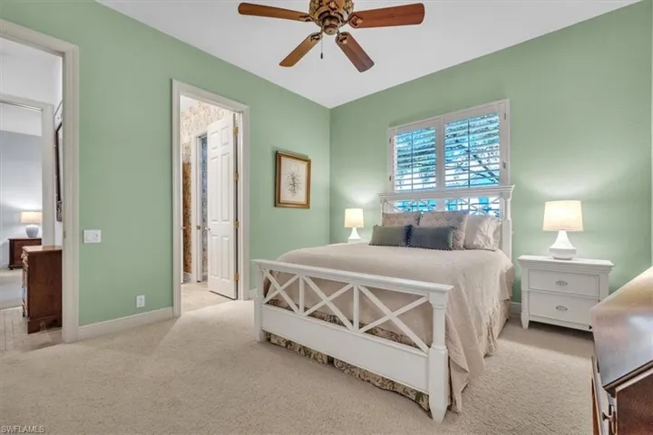 Bedroom with light carpet, connected bathroom, and a ceiling fan