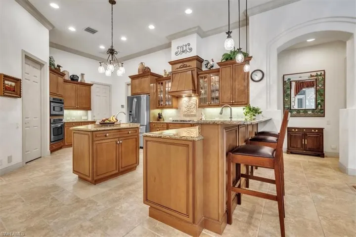 Kitchen featuring wood finish cabinets, decorative backsplash, a breakfast bar area, glass insert cabinets, and light stone counters