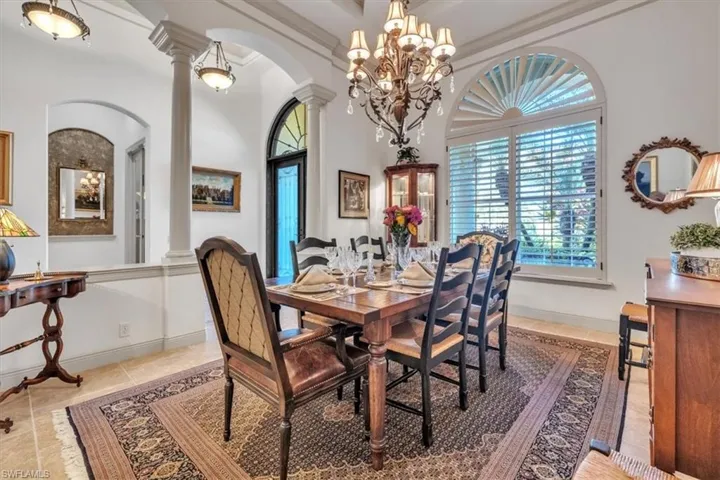 Dining room with arched walkways, decorative columns, a chandelier, and a high ceiling
