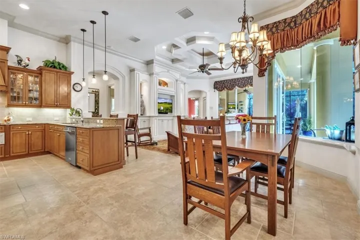 Dining area featuring coffered ceiling, crown molding, arched walkways, ceiling fan, and hanging lights