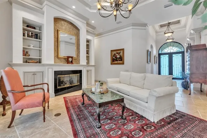 Living area with built in features, a chandelier, french doors, a fireplace, and crown molding