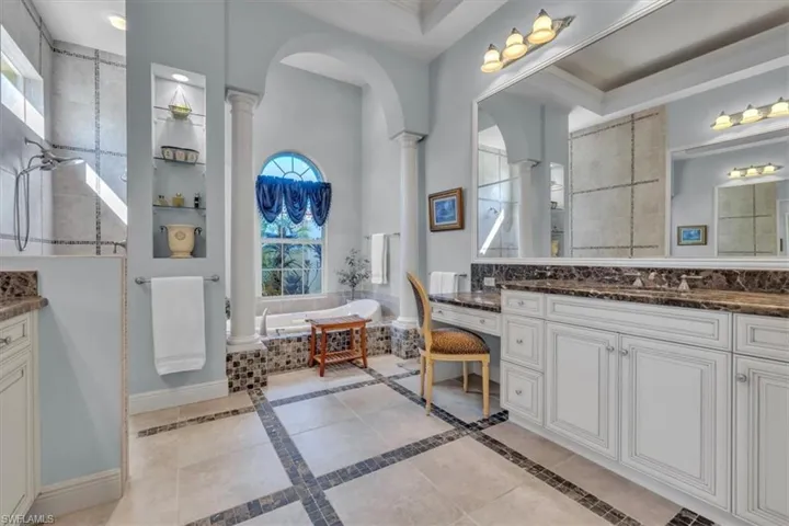 Full bath featuring a walk in shower, vanity, decorative columns, and a garden tub