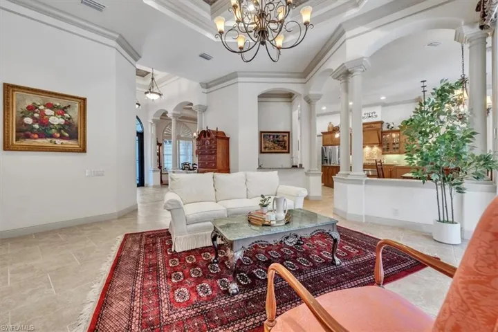 Living area with arched walkways, ornamental molding, ornate columns, a high ceiling, and hanging lights