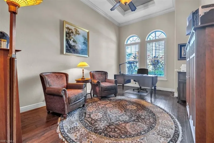 Office space featuring dark wood-style flooring, crown molding, and ceiling fan