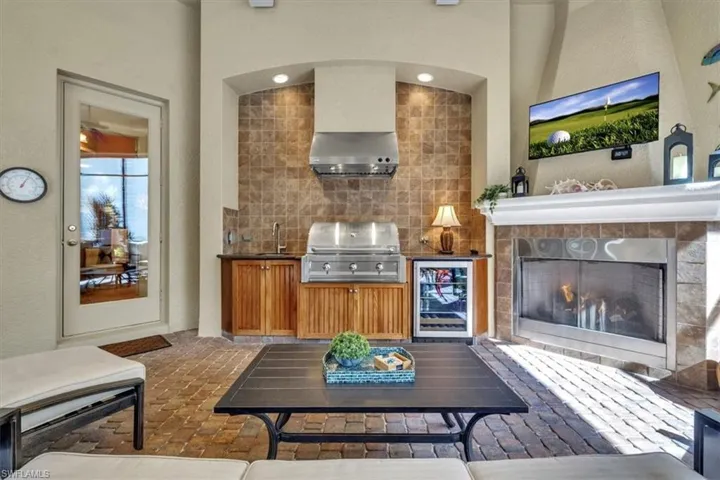Living room featuring a tile fireplace, wine cooler, a textured wall, and brick flooring