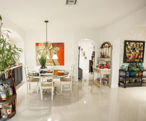 Dining space with arched walkways and light tile patterned floors