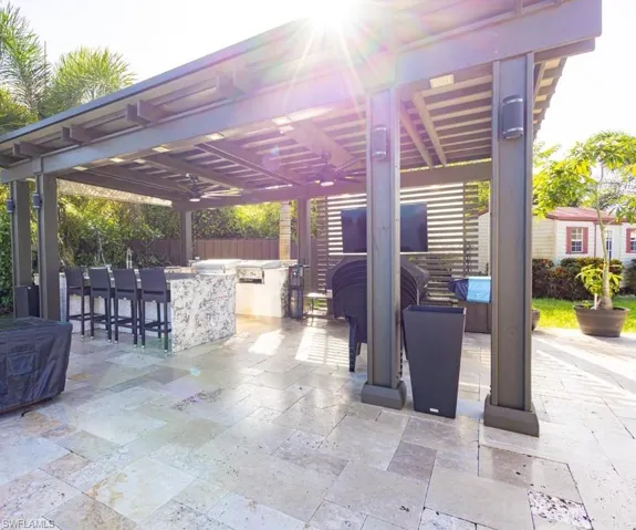 View of patio with area for grilling and a pergola