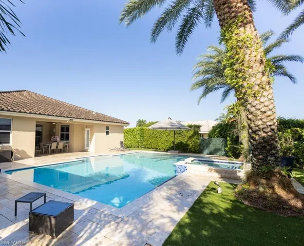 View of swimming pool featuring a patio, a pool with connected hot tub, and a yard