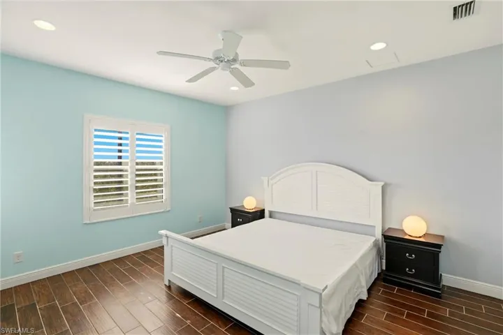 Bedroom with wood tiled floors, a ceiling fan, and recessed lighting