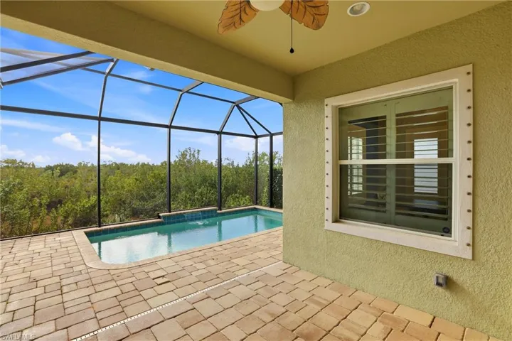 Outdoor pool with a patio area, a sunroom, and glass enclosure