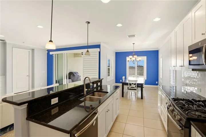 Kitchen with white cabinets, decorative light fixtures, dark stone counters, stainless steel appliances, and recessed lighting