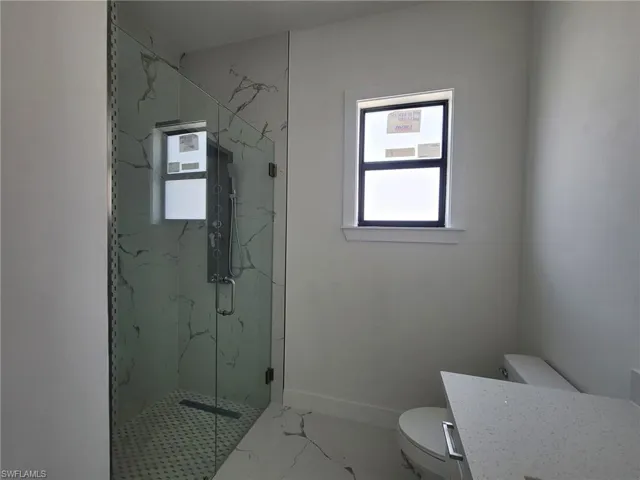 Bathroom featuring walk in shower, vanity, and toilet