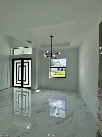 Unfurnished dining area featuring a chandelier and a tray ceiling