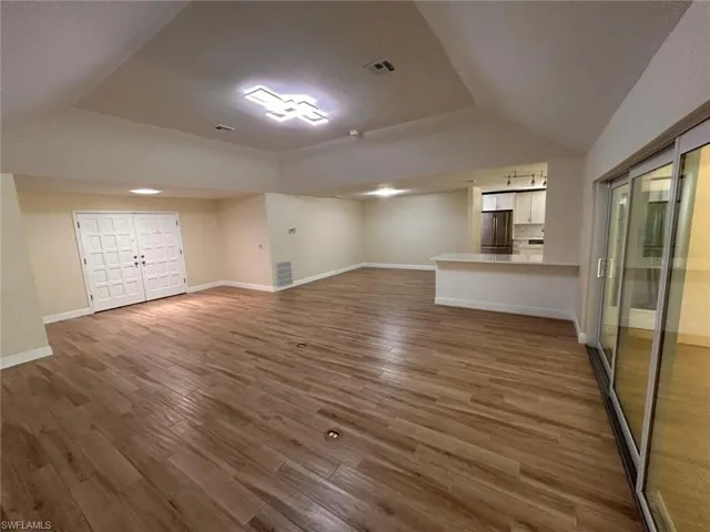 Unfurnished living room with dark wood-type flooring and a raised ceiling
