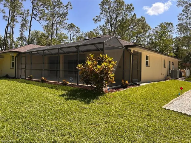 Rear view of house with a lanai, a lawn, stucco siding, and a sunroom
