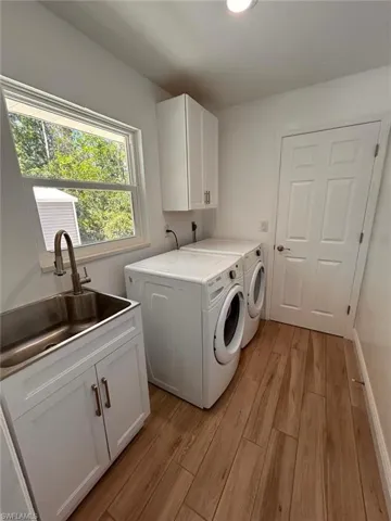 Laundry room featuring light wood-style floors, washer and dryer, cabinet space, and recessed lighting