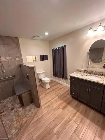 Bathroom with vanity, a walk in shower, light wood-style floors, and recessed lighting