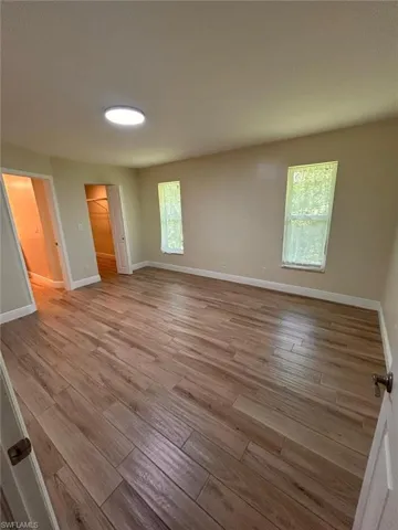 Unfurnished bedroom with a walk in closet and light wood finished floors